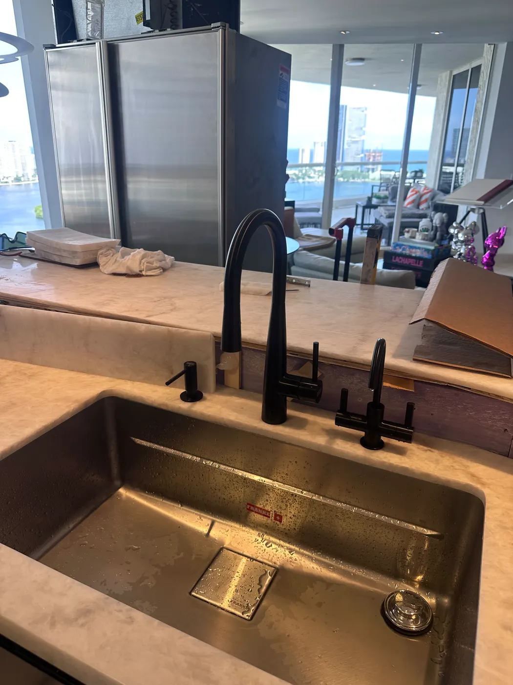 A new undermount stainless kitchen sink with a matte black pull-down faucet, freshly installed
