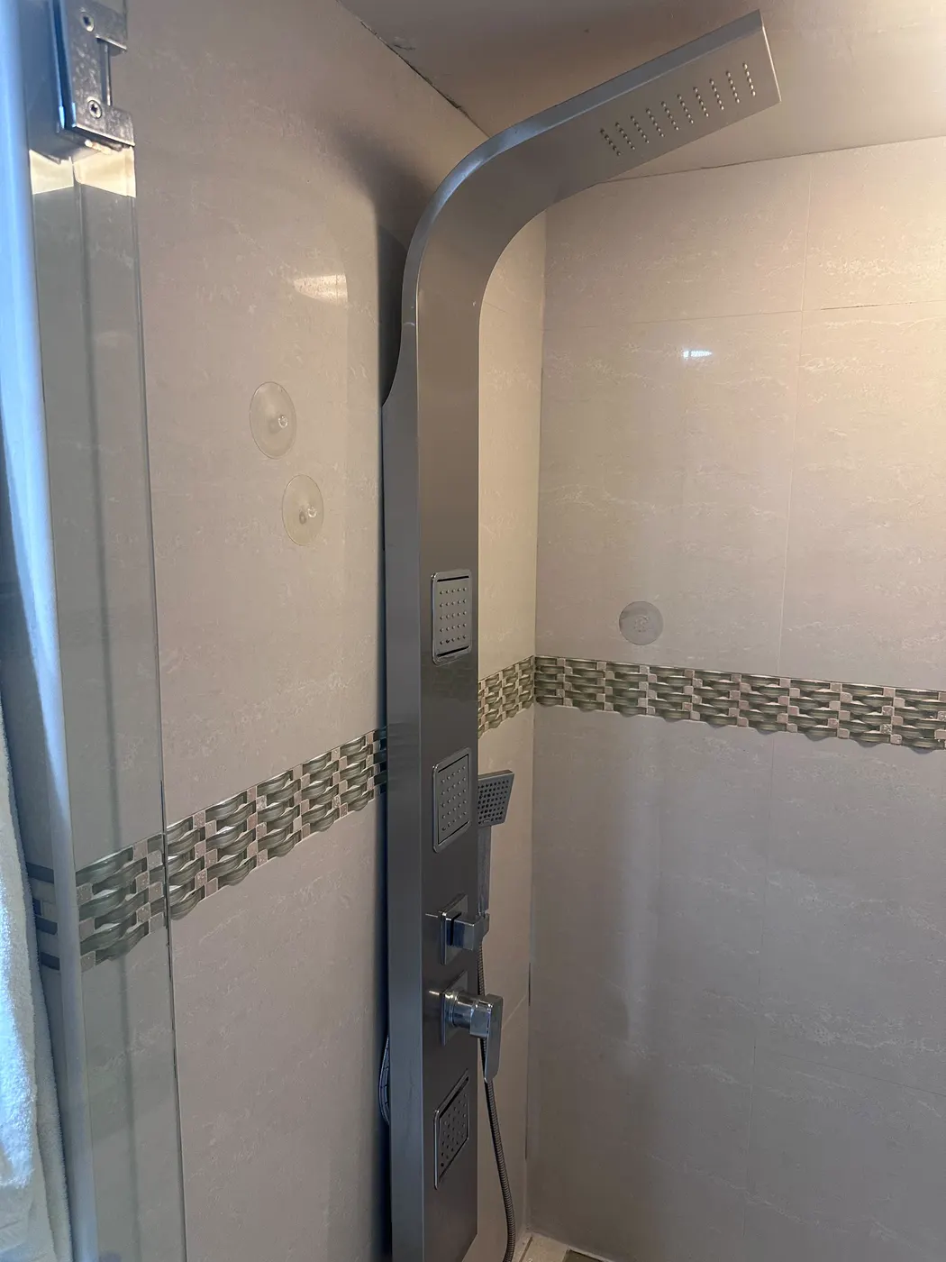 New brushed-steel shower panel with rain head and body jets installed on a tiled shower wall