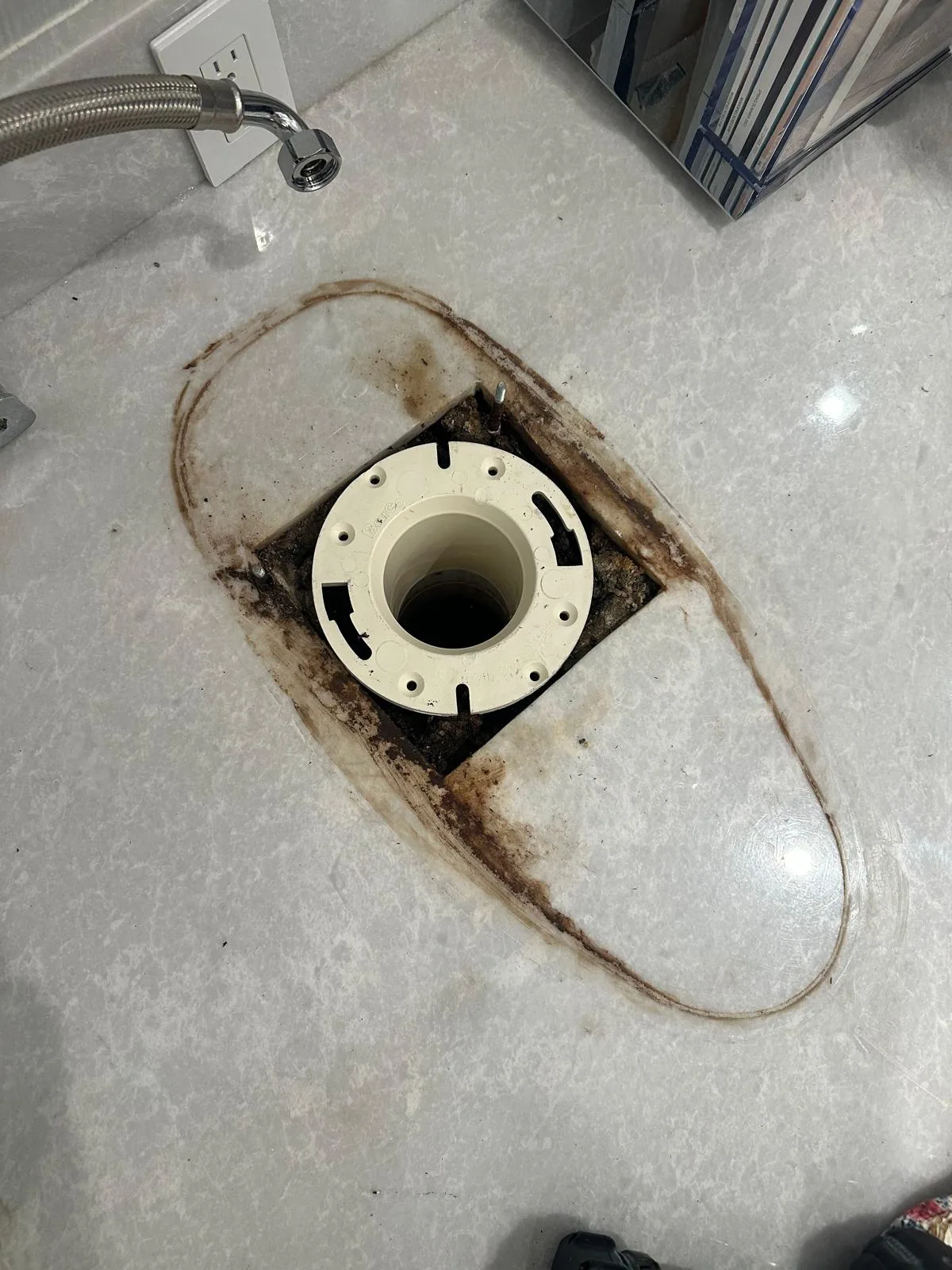 A new toilet flange set in the floor, clean and ready for the toilet
